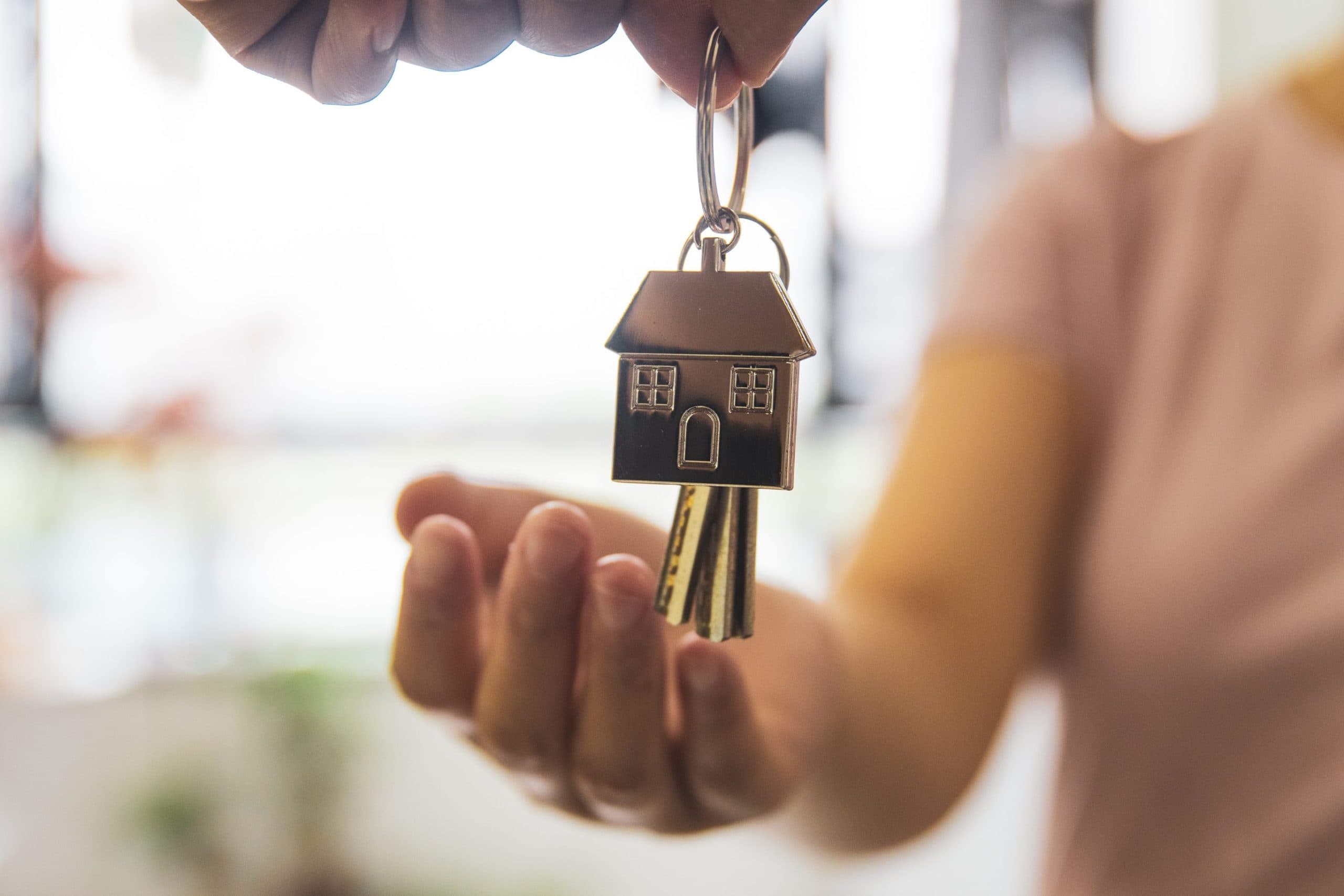 A hand holding a house key on a house-shaped keyring