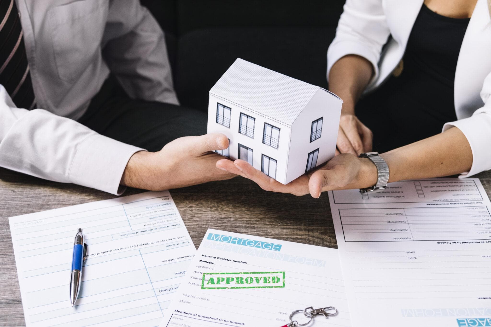 A model house handed across an approved mortgage application